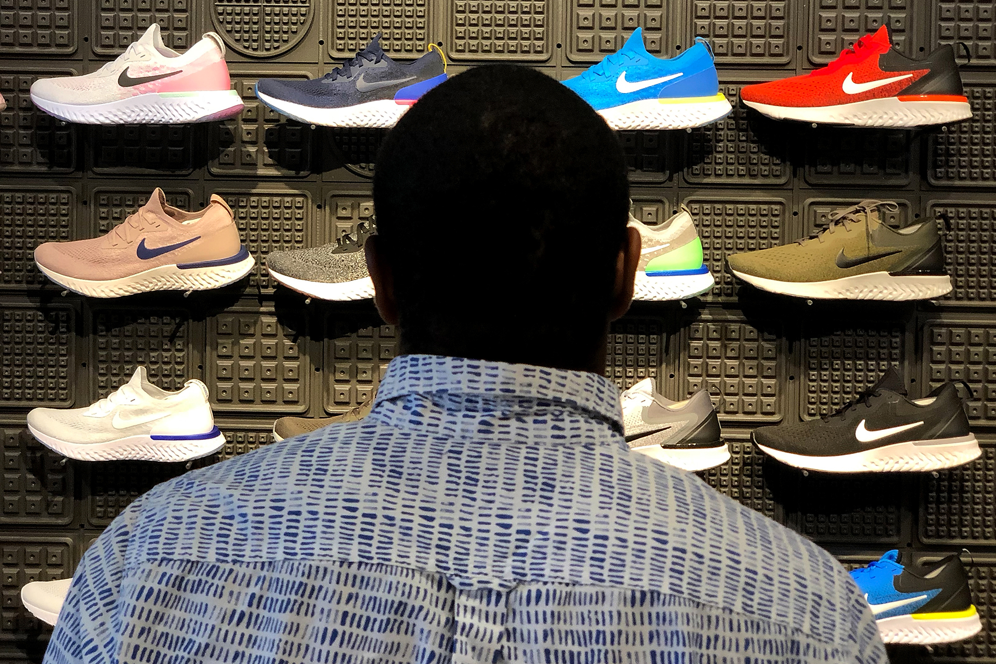 Man looking at window display of various Nike sneakers